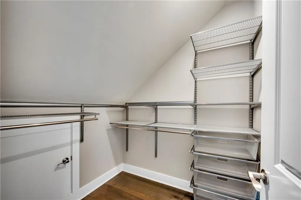 Walk in closet with dark wood-style flooring and vaulted ceiling