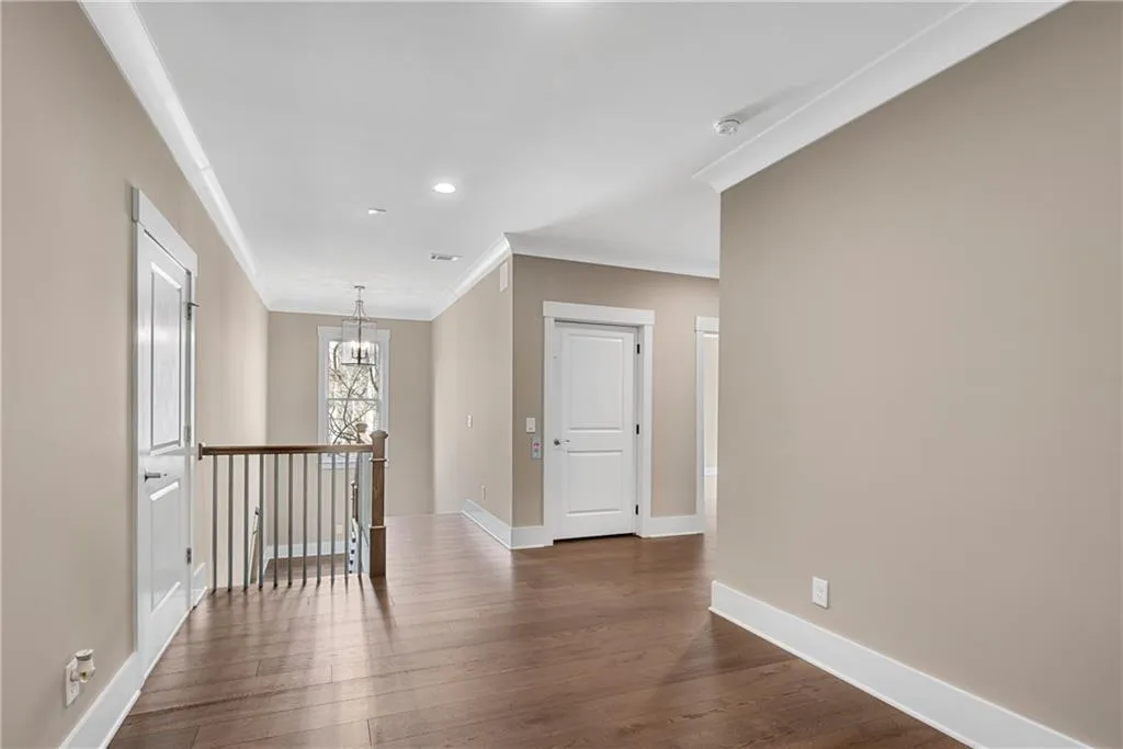 Unfurnished room with crown molding, dark wood-style floors, and suspended lighting