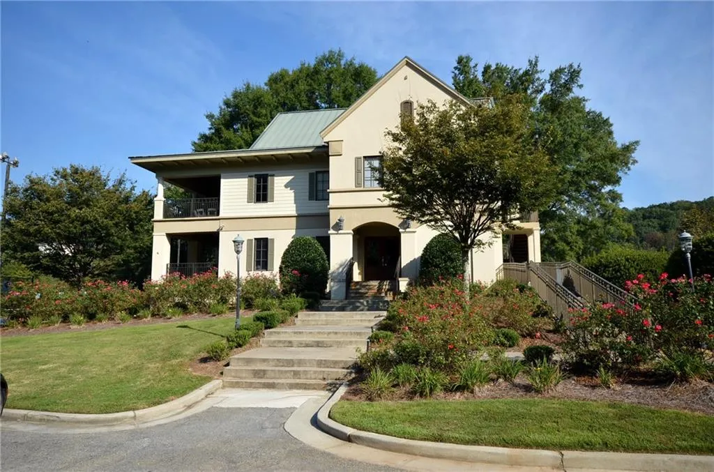 View of front facade with stucco siding, a front lawn, a metal roof, and a balcony