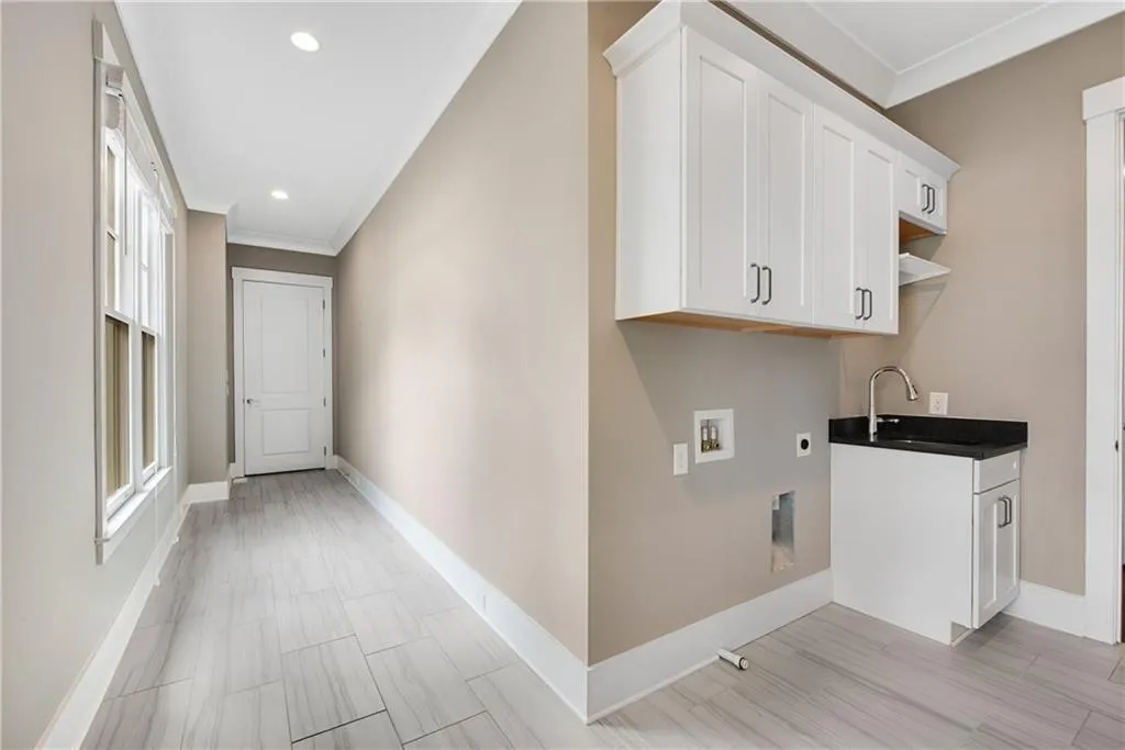 Laundry area with crown molding, hookup for a washing machine, cabinet space, hookup for an electric dryer, and recessed lighting