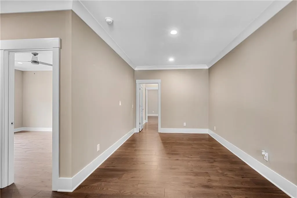 Empty room featuring dark wood finished floors, recessed lighting, and ornamental molding