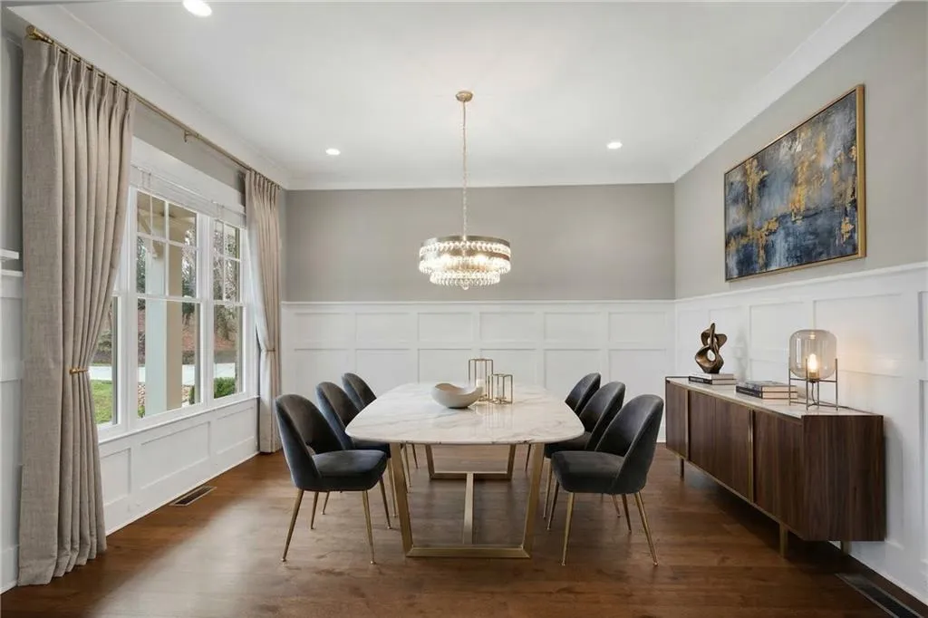 Dining space with a decorative wall, wainscoting, hanging lights, crown molding, and dark wood-style floors
