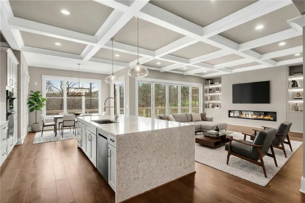Kitchen featuring white cabinetry, light stone counters, a center island with sink, dark wood-style flooring, and built in features