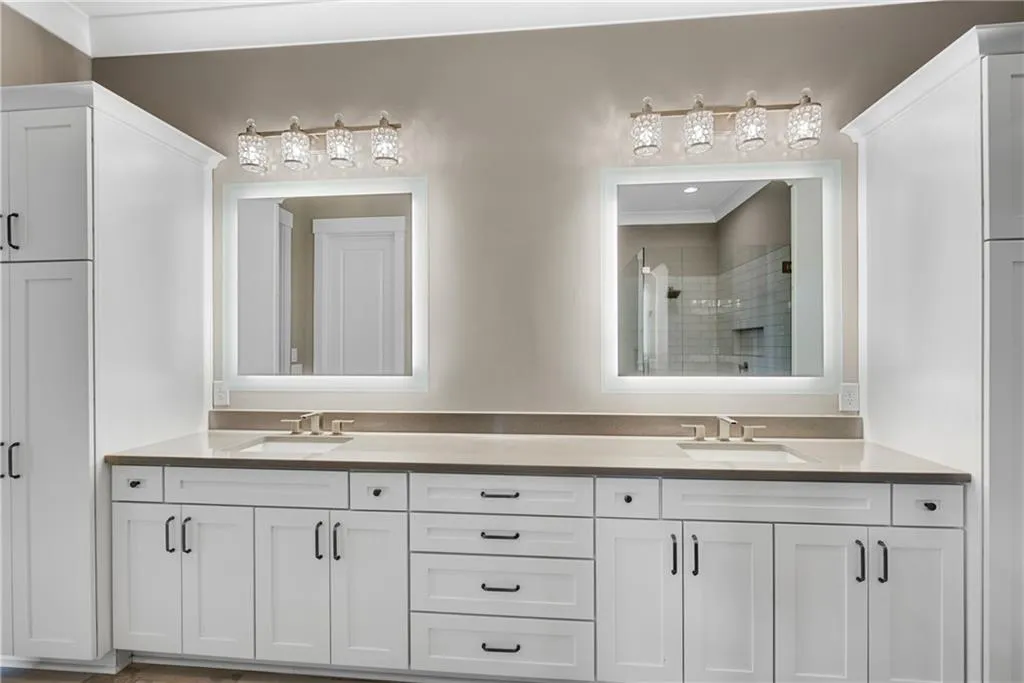 Full bathroom with double vanity, a shower stall, and ornamental molding