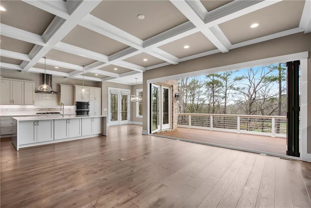 Unfurnished living room with french doors, dark wood finished floors, coffered ceiling, and hanging lights