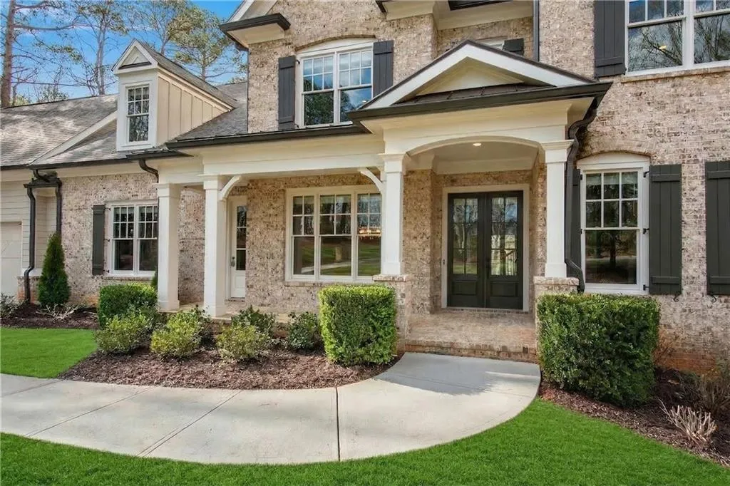 Property entrance with french doors, covered porch, and brick siding