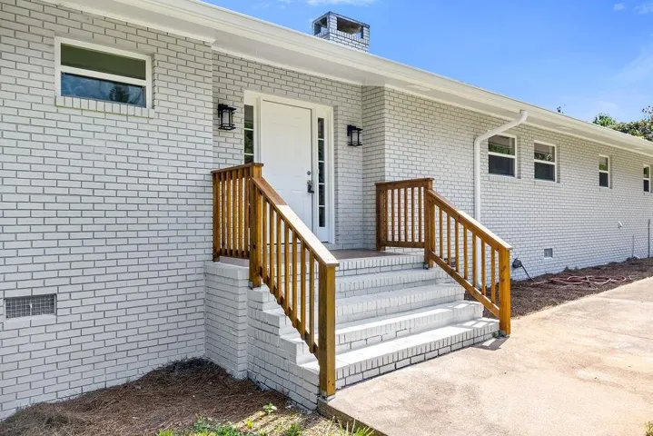 Brick exterior with a white finish, featuring a prominent front entrance with a white door and sidelights