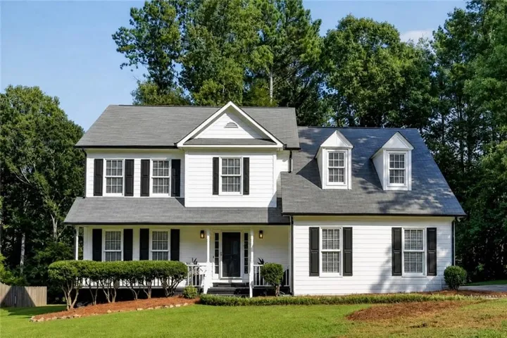 Two-story residence featuring white siding and black shutters