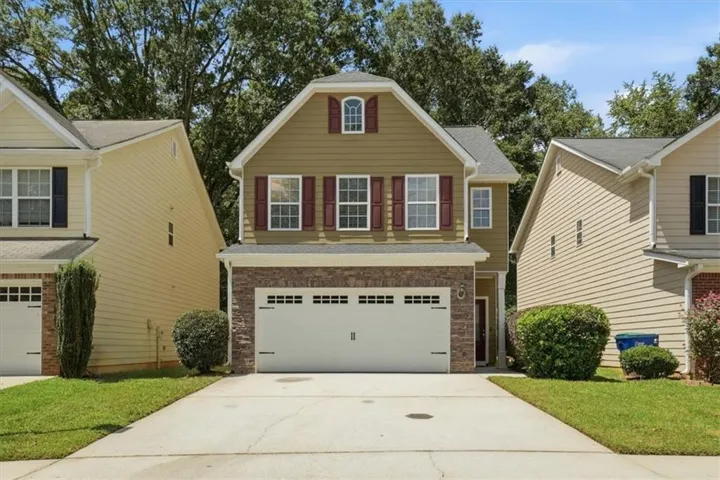 Two-story residence featuring a two-car garage, brick façade detailing, and decorative window shutters