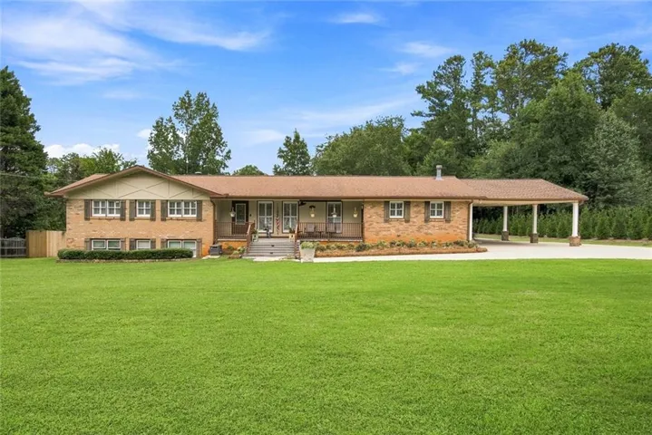 Brick exterior residence featuring a covered carport, multiple windows with shutters, and a front porch