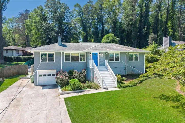 Ranch-style residence featuring a prominent front staircase, a vibrant blue entry door, and a built-in garage