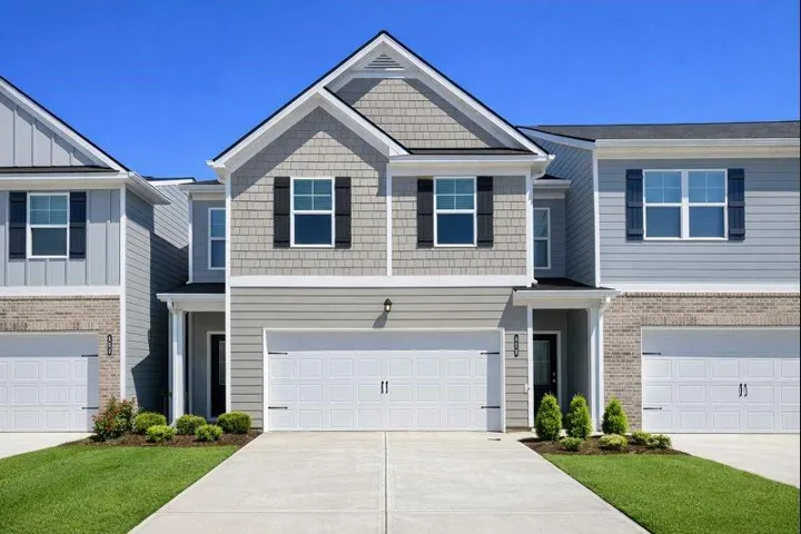 Two-story residence featuring light gray siding, dark shutters, a front-facing gable, and an attached two-car garage