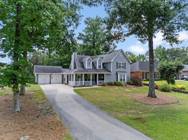 Gable-front home featuring gray siding, a covered porch with white columns, and a double-door garage