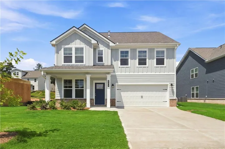 Two-story residence featuring light gray siding, white trim, and a dark blue entry door