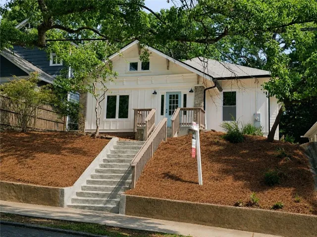 White board and batten exterior with a light blue front door and natural wood railings