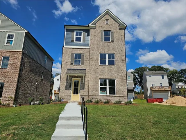 Three-story brick exterior with blue siding accents, featuring a prominent gable roofline and multiple windows with dark shutters