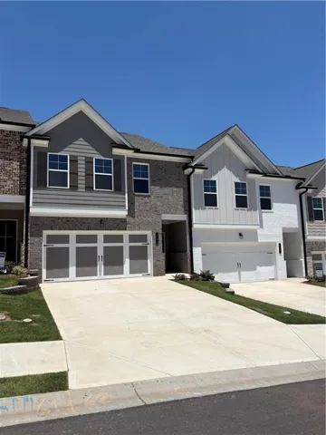 View of front of house with a garage, driveway, board and batten siding, and brick siding