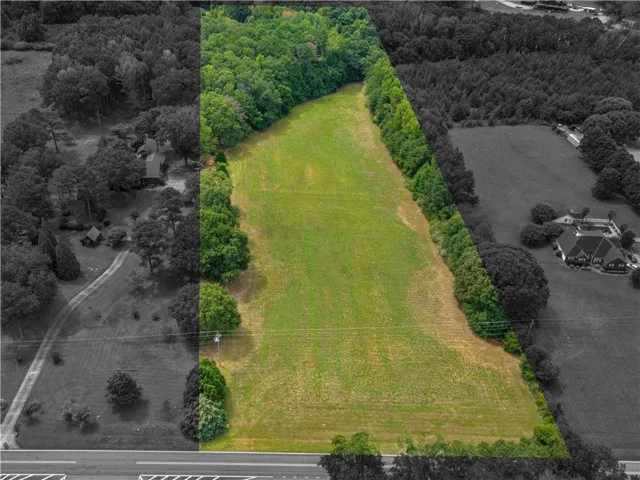 Expansive pastoral grounds featuring a substantial manicured lawn bordered by mature tree lines on both sides, creating a serene landscape setting