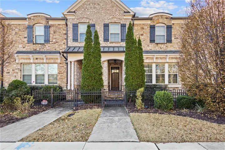 View of front of house featuring a gate, brick siding, a fenced front yard, and a porch