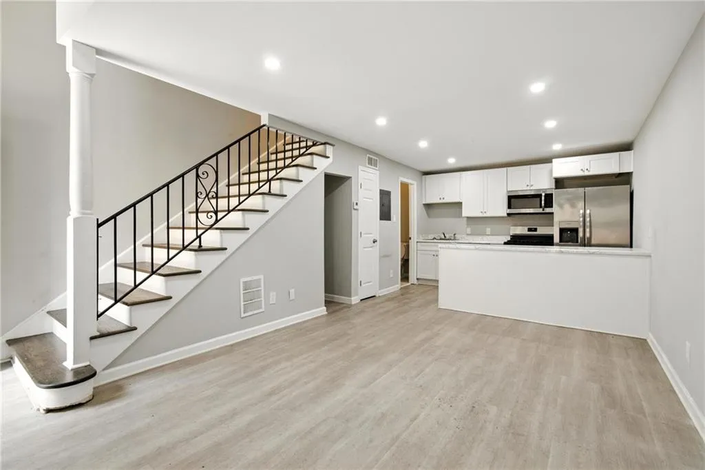 Unfurnished living room featuring recessed lighting, light wood finished floors, and stairway