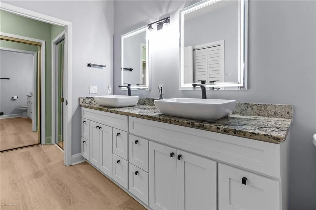 Full bath featuring double vanity and wood finished floors
