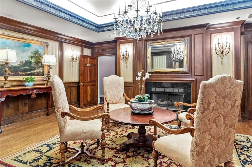 Living area with a high end fireplace, a chandelier, wood finished floors, wood walls, and crown molding