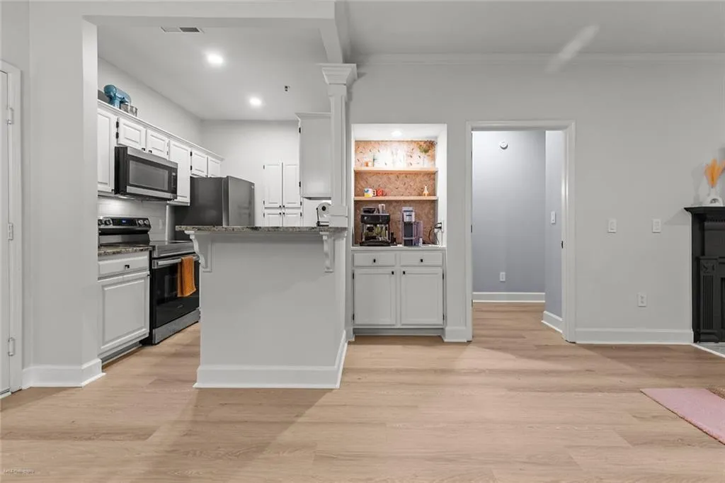 Kitchen with appliances with stainless steel finishes, white cabinets, a peninsula, light wood-type flooring, and recessed lighting