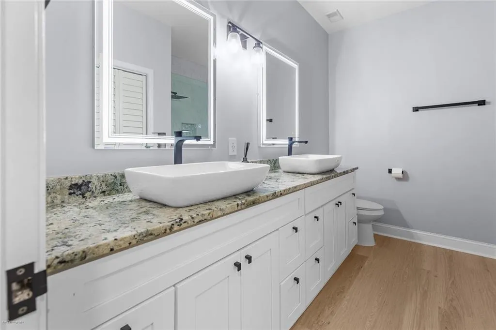 Full bathroom with double vanity, wood finished floors, and a shower