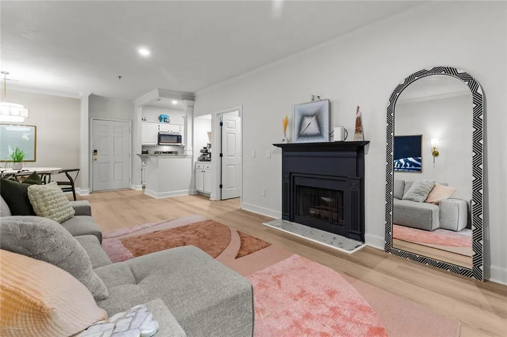 Living room featuring crown molding, light wood finished floors, a fireplace with raised hearth, and recessed lighting