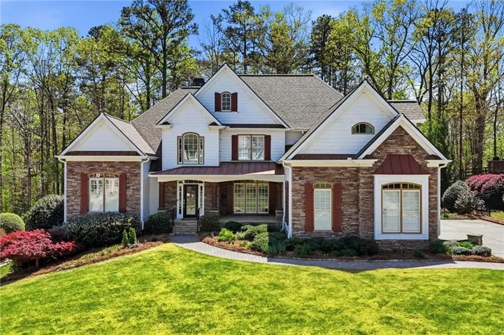 Craftsman inspired home featuring stone siding, covered porch, a front lawn, and a shingled roof