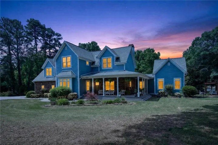 Blue siding exterior with dormer windows, a full-width covered porch, and a brick foundation accent