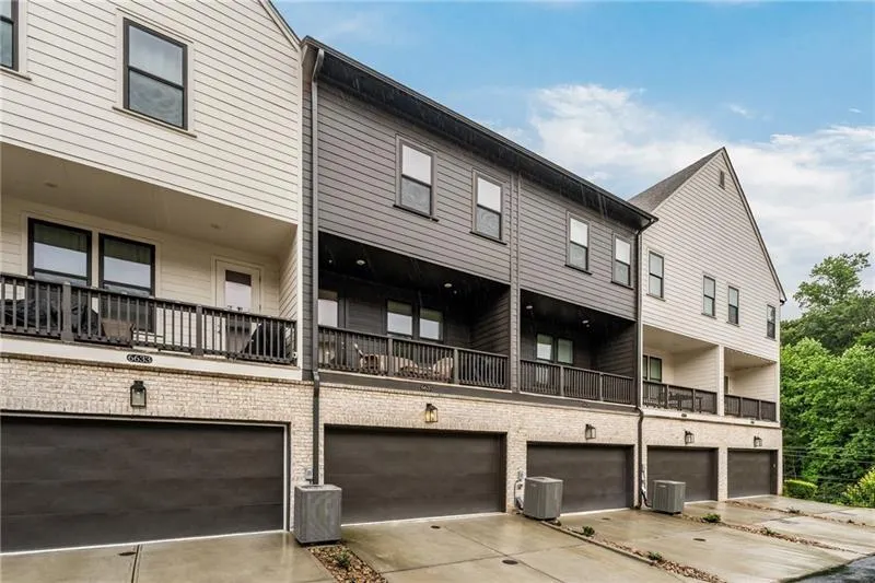 Back of house with an attached garage, driveway, and a balcony