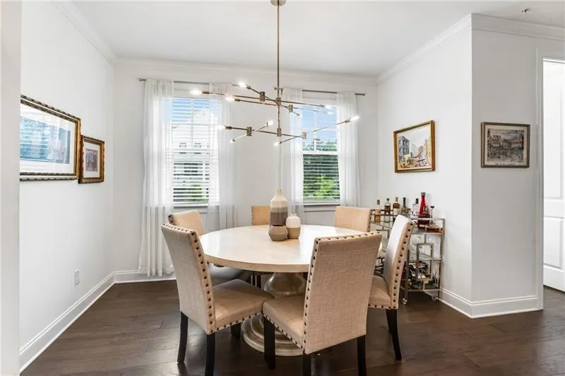 Dining room with dark wood-type flooring, crown molding, and a chandelier