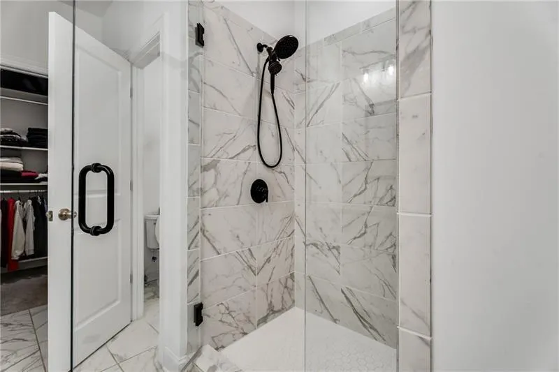 Bathroom featuring a walk in closet, a marble finish shower, and marble finish flooring