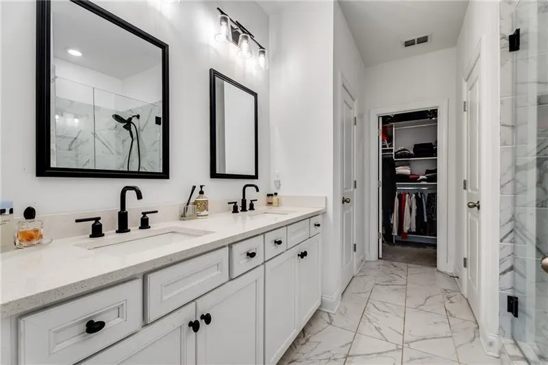 Bathroom featuring a marble finish shower, light marble finish flooring, and a walk in closet
