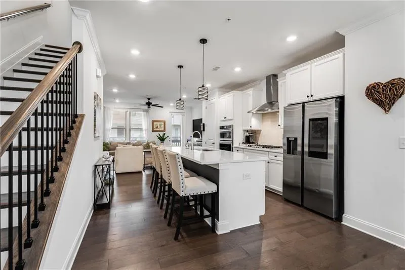 Kitchen with open floor plan, hanging light fixtures, an island with sink, appliances with stainless steel finishes, and white cabinetry