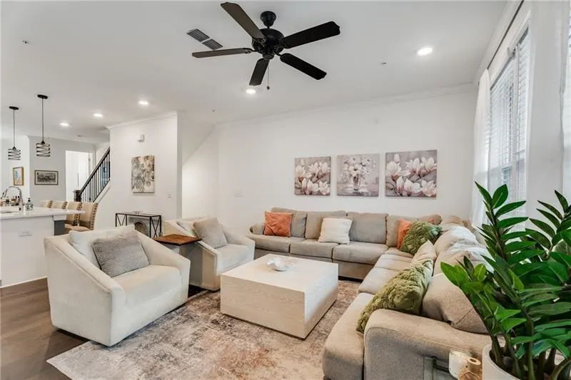 Living room with ornamental molding, a ceiling fan, recessed lighting, stairway, and wood finished floors