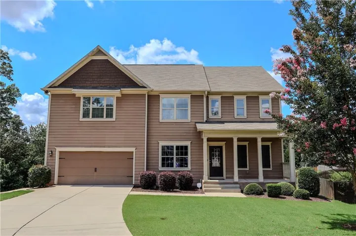 View of front of home with covered porch, an attached garage, concrete driveway, and roof with shingles