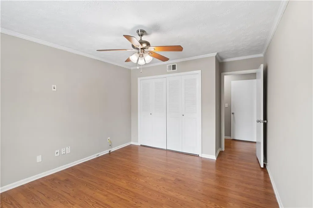 Unfurnished bedroom with wood finished floors, ceiling fan, ornamental molding, a closet, and a textured ceiling