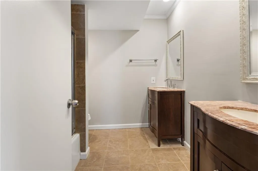 Bathroom with two vanities, crown molding, and shower / bath combination