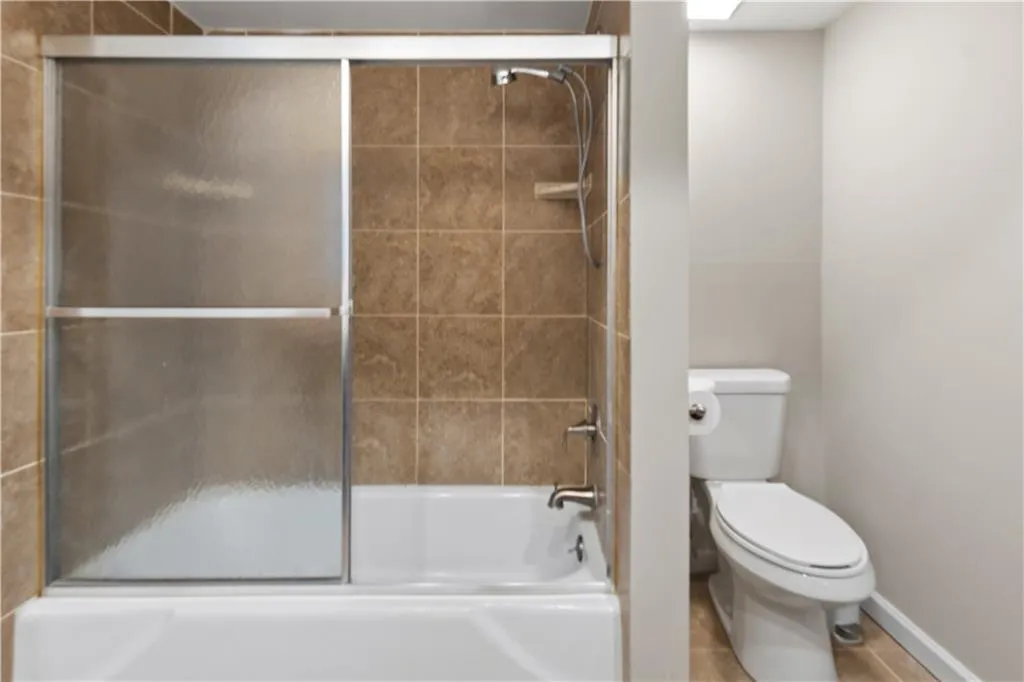 Full bath featuring enclosed tub / shower combo and tile patterned floors