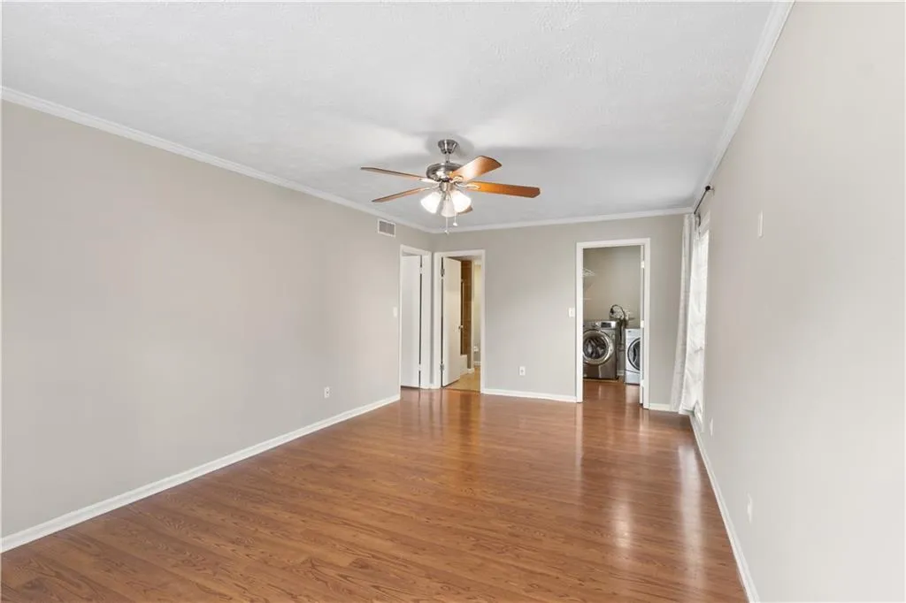 Unfurnished room with ornamental molding, dark wood-type flooring, a ceiling fan, and separate washer and dryer