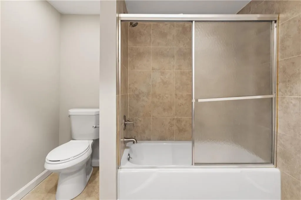 Bathroom featuring enclosed tub / shower combo and light tile patterned floors