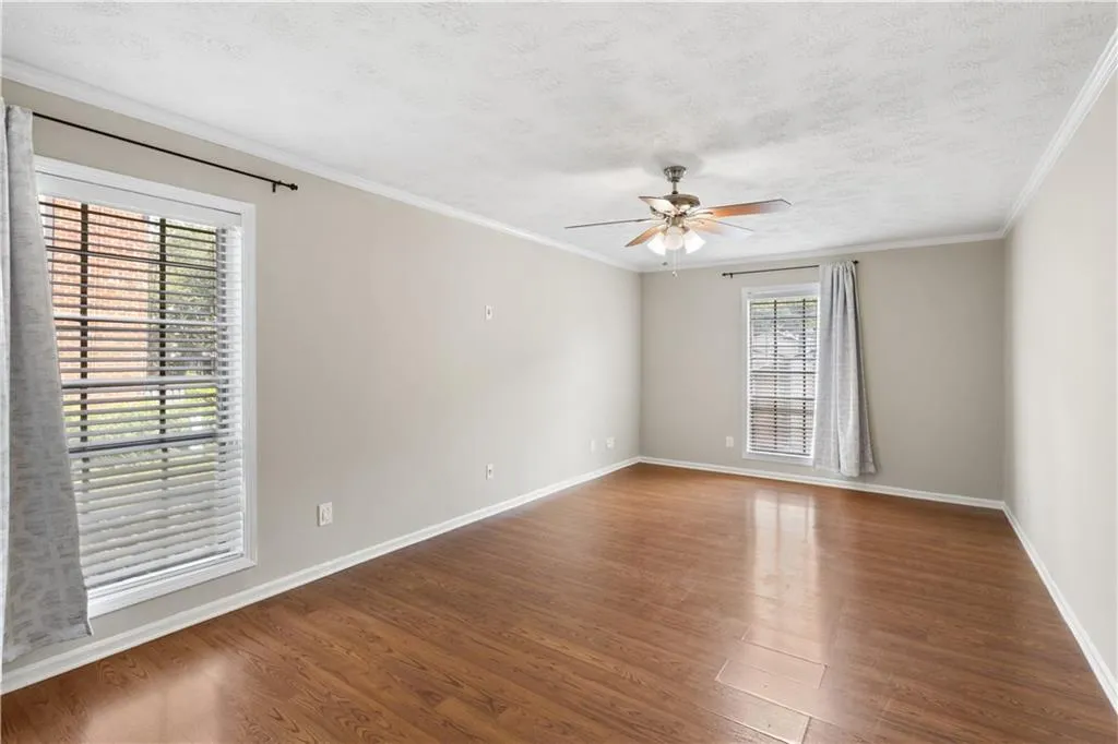 Empty room with dark wood-type flooring, a ceiling fan, a textured ceiling, and crown molding
