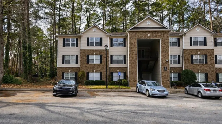 Three-story building with light-colored siding and stone-finish accents