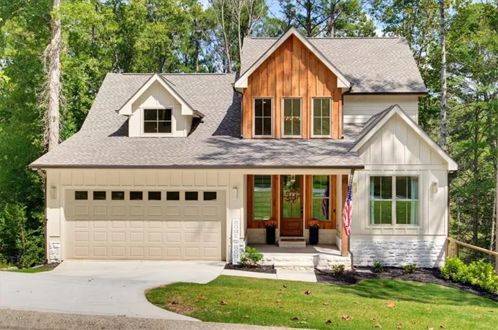 Gable roof with dormer, wood siding accent, board and batten siding, stone facade, and attached garage