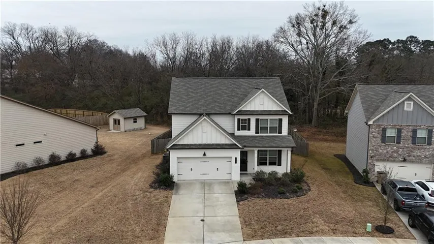 Two-story residence featuring a white facade with dark shutters, an attached two-car garage, and a concrete driveway