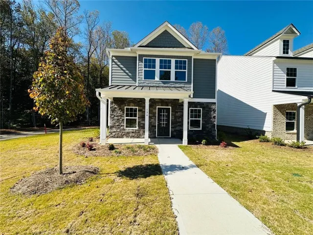 Grey siding exterior with stone veneer accents, covered front porch, white columns, and a concrete walkway