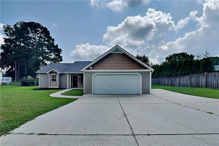 Exterior featuring a two-car garage, concrete driveway, and a shingle roof
