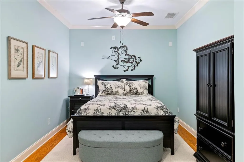 Bedroom with light wood-type flooring, ceiling fan, and crown molding